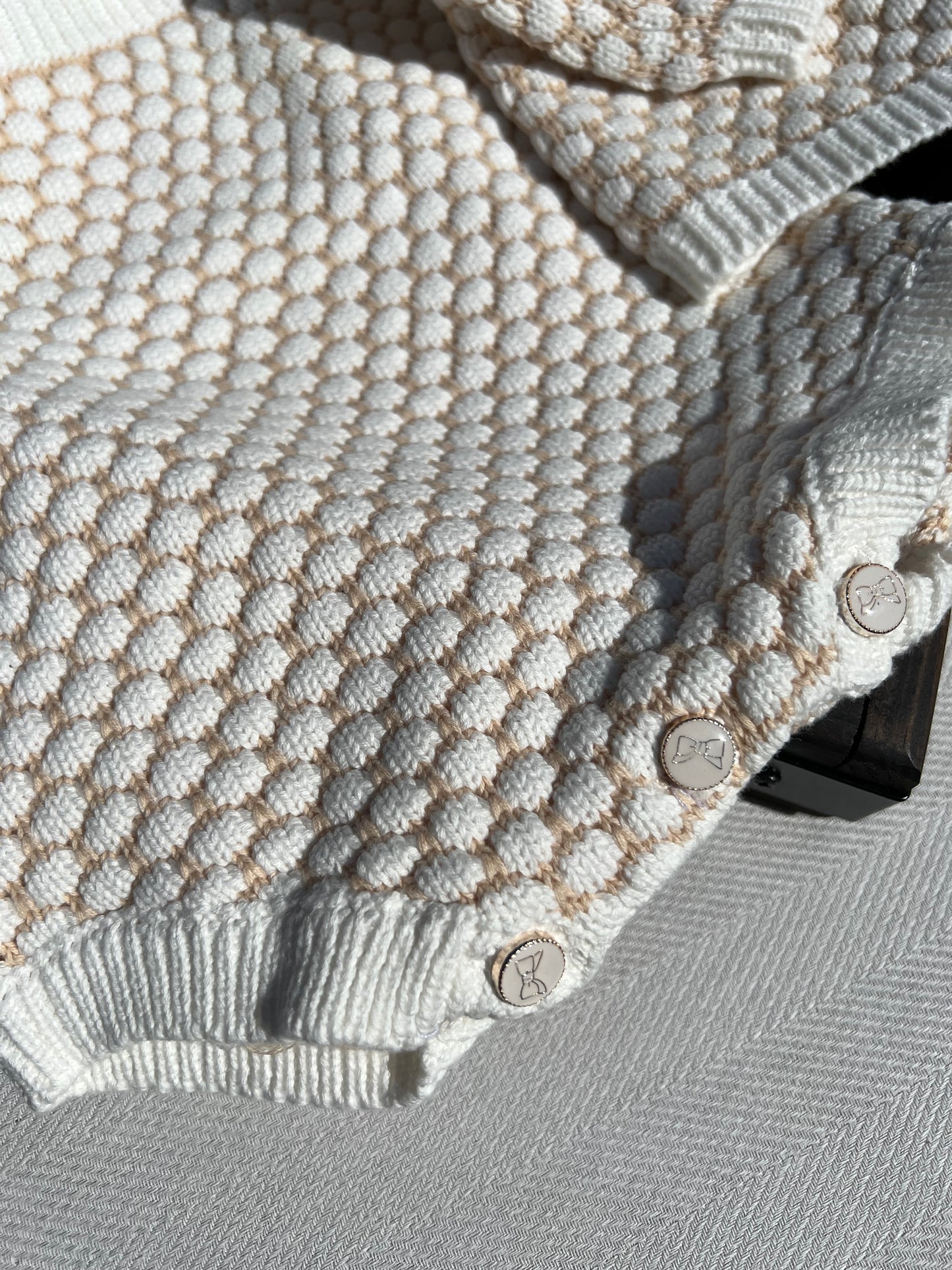 Honeycomb Pattern Knitted Baby Romper with Button-up Bottom Closure, Buttons are White with Gold Printed Bows and a Gold Rim