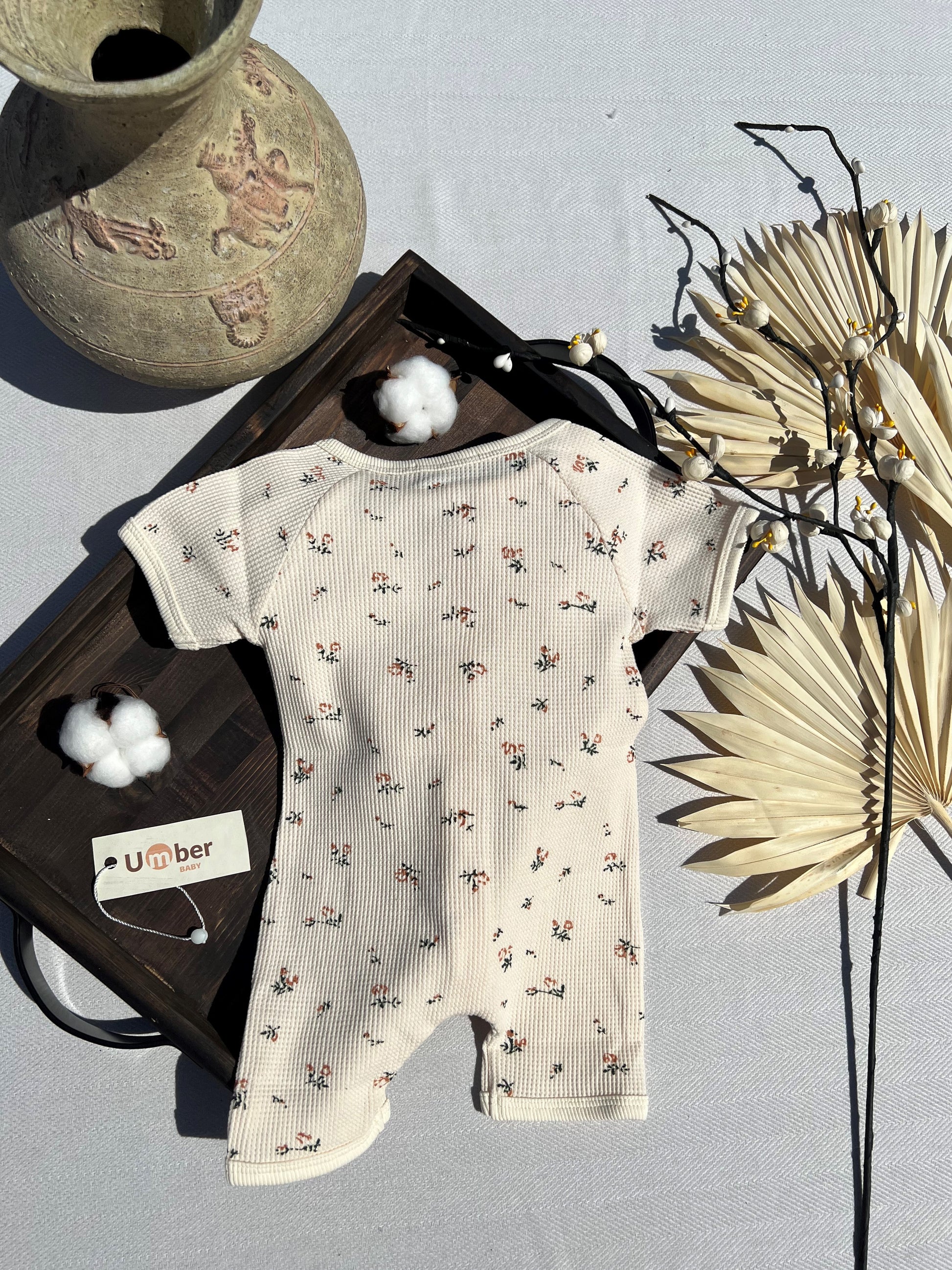 Back of Beige Short Sleeve Button-up Waffle Baby Romper with Small Pink Flower Pattern