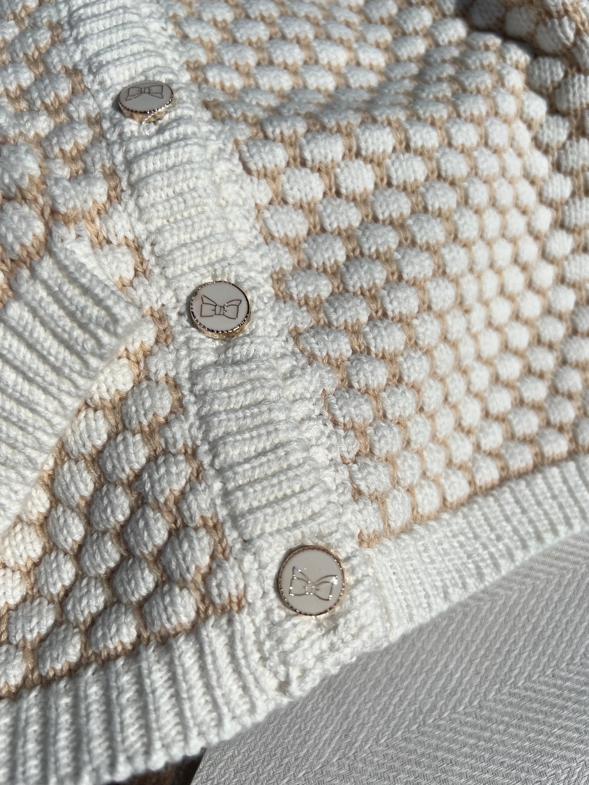Honeycomb Pattern Knitted Baby Button-up Cardigan, Buttons are White with Gold Printed Bows and a Gold Rim